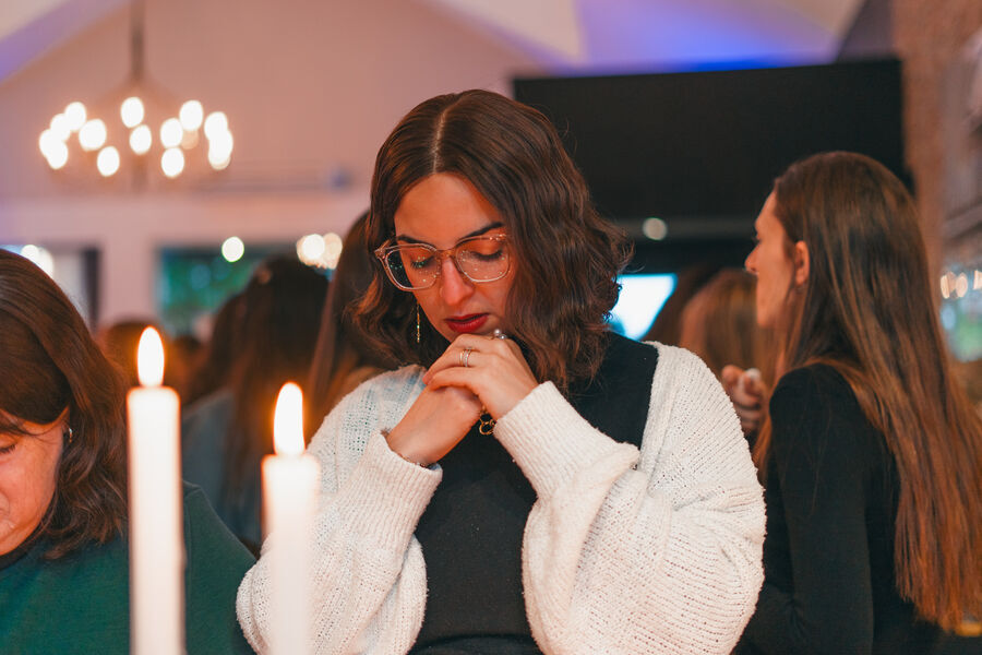 Joven rezando frente a las velas encendidas